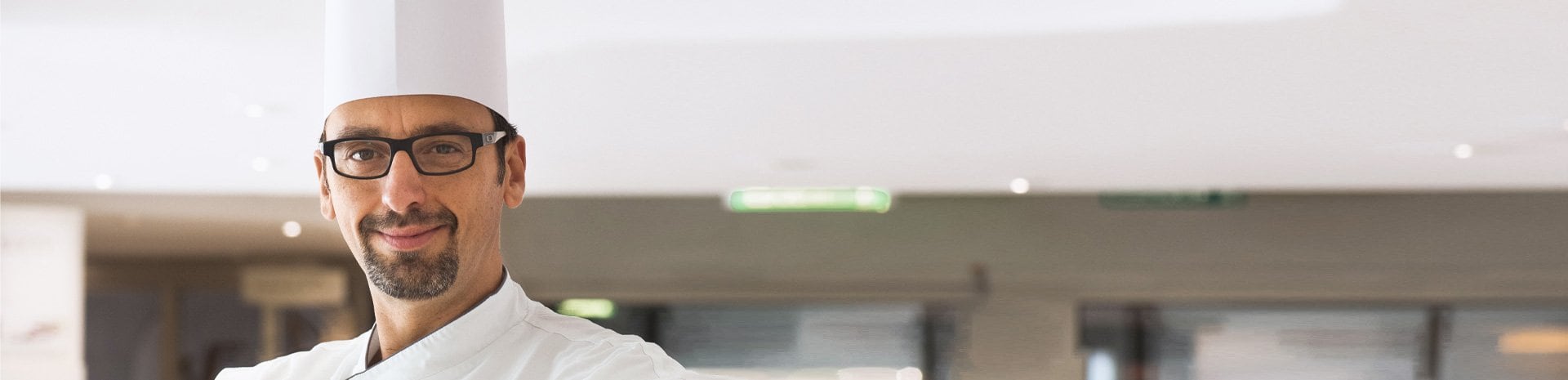 A chef in a white uniform and tall hat in a modern cruise ship dining area | MSC Cruises A chef in a white uniform and tall hat in a modern cruise ship dining area | MSC Cruises