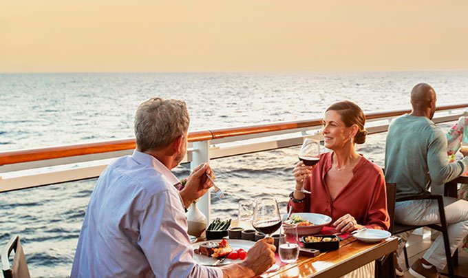 Couple dining on a cruise ship deck overlooking the ocean at sunset | MSC Cruises