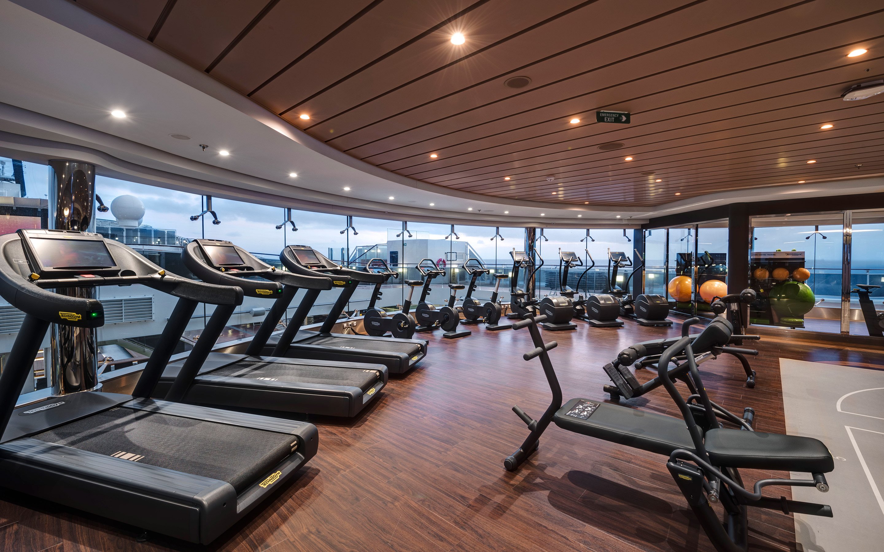 Modern fitness center with treadmills and exercise equipment overlooking the ocean | MSC Cruises Modern fitness center with treadmills and exercise equipment overlooking the ocean | MSC Cruises